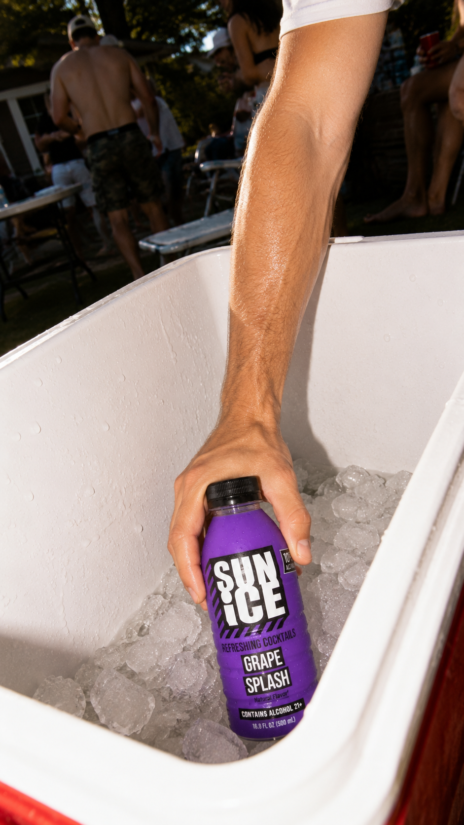 Hand reaching into a cooler for Grape Splash SUN ICE.